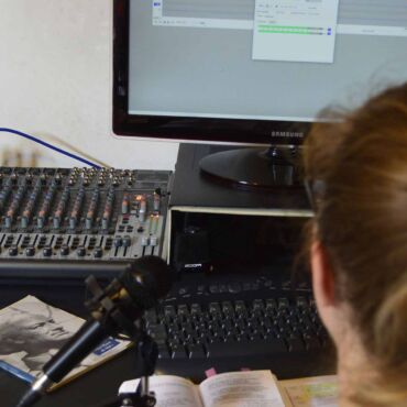 Person sitzt an Mischpult und Mikrofon vor Audio-Bildschirm – Screenreader: wie blinde Nutzer Websites bedienen