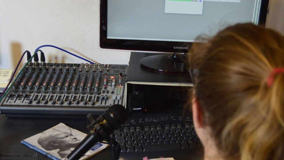 Person sitzt an Mischpult und Mikrofon vor Audio-Bildschirm – Screenreader: wie blinde Nutzer Websites bedienen