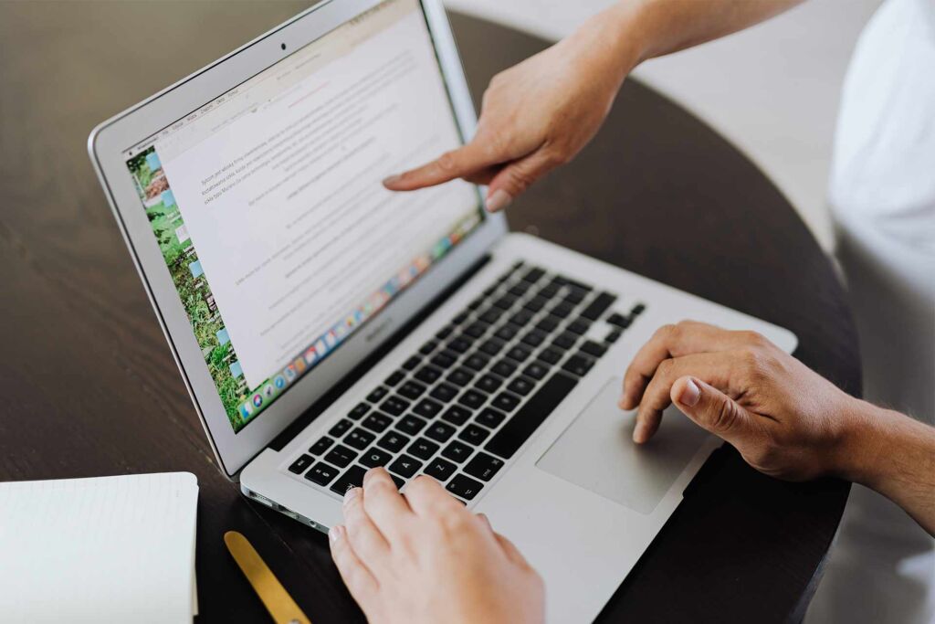 Hand zeigt auf Textabsatz im Dokument am Laptop – PDF/UA: der Standard für barrierefreie PDFs erklärt