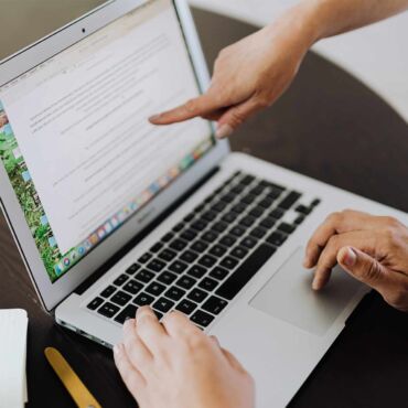 Hand zeigt auf Textabsatz im Dokument am Laptop – PDF/UA: der Standard für barrierefreie PDFs erklärt