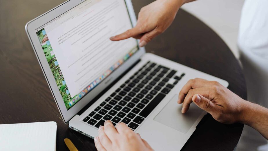 Hand zeigt auf Textabsatz im Dokument am Laptop – PDF/UA: der Standard für barrierefreie PDFs erklärt