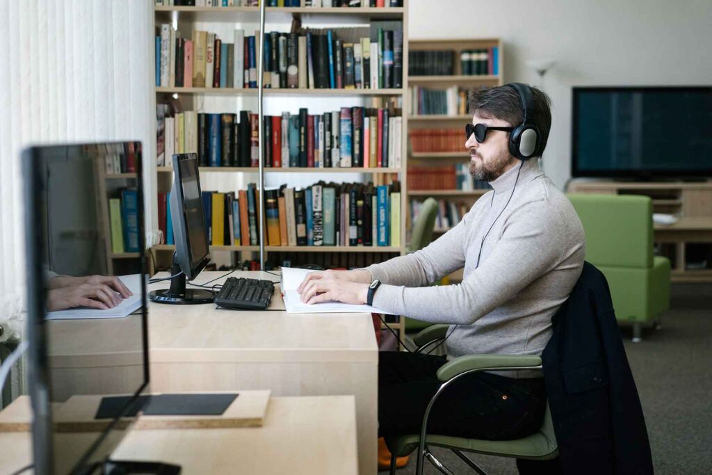 Blinder Mann mit Kopfhörern arbeitet per Tastatur am Bildschirm – Screenreader-Zugriff verständlich erklärt