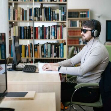 Blinder Mann mit Kopfhörern arbeitet per Tastatur am Bildschirm – Screenreader-Zugriff verständlich erklärt