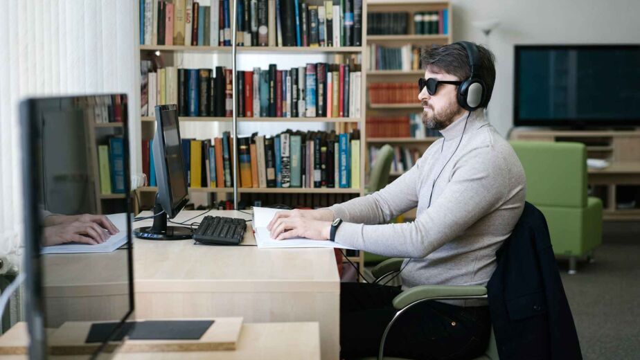 Blinder Mann mit Kopfhörern arbeitet per Tastatur am Bildschirm – Screenreader-Zugriff verständlich erklärt