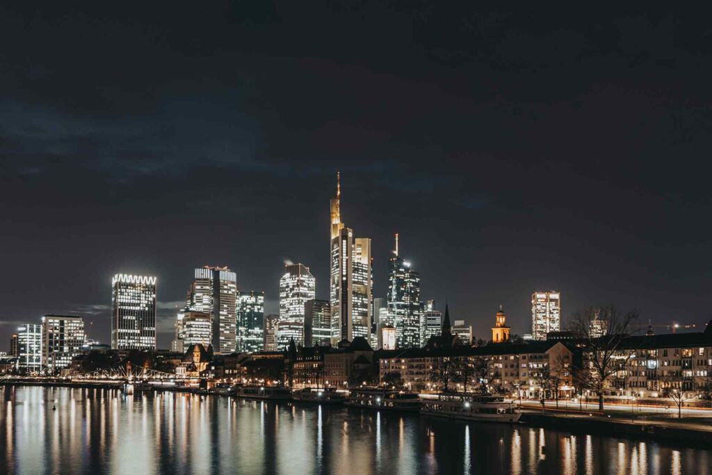 Beleuchtete Skyline einer Großstadt bei Nacht am Fluss – barrierefreie Smart City für digitale Teilhabe aller