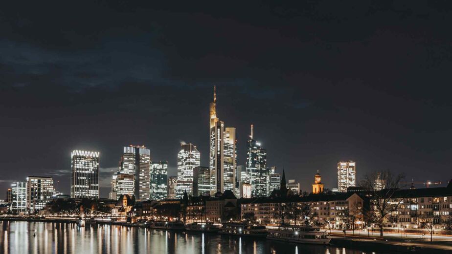 Beleuchtete Skyline einer Großstadt bei Nacht am Fluss – barrierefreie Smart City für digitale Teilhabe aller