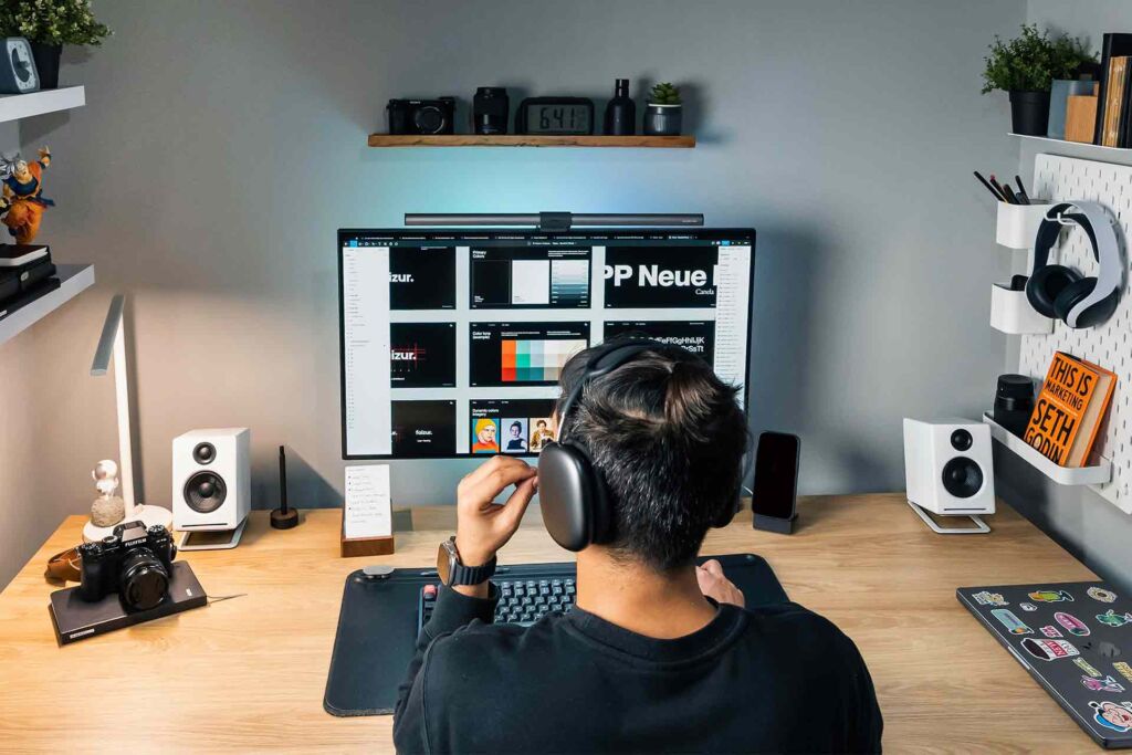 Designer mit Kopfhörern arbeitet am Monitor mit Farbpalette – WCAG 2.2 Trends für digitale Barrierefreiheit