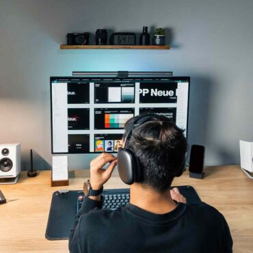 Designer mit Kopfhörern arbeitet am Monitor mit Farbpalette – WCAG 2.2 Trends für digitale Barrierefreiheit