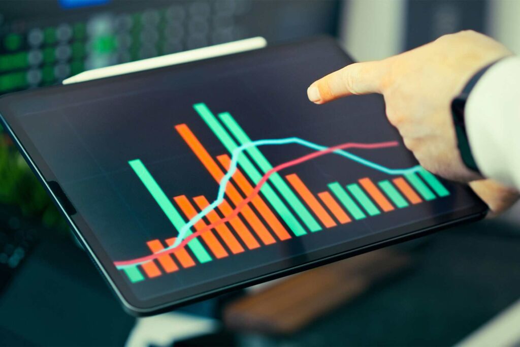Hand zeigt auf Balken- und Liniendiagramm am Tablet – wirtschaftlicher Nutzen der Barrierefreiheit in Zahlen