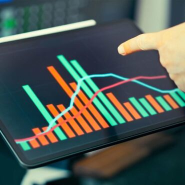Hand zeigt auf Balken- und Liniendiagramm am Tablet – wirtschaftlicher Nutzen der Barrierefreiheit in Zahlen