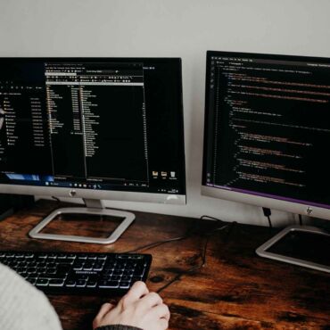 Programmierer schreibt HTML-Code an zwei Bildschirmen – barrierefreie Webentwicklung: semantisches HTML und ARIA